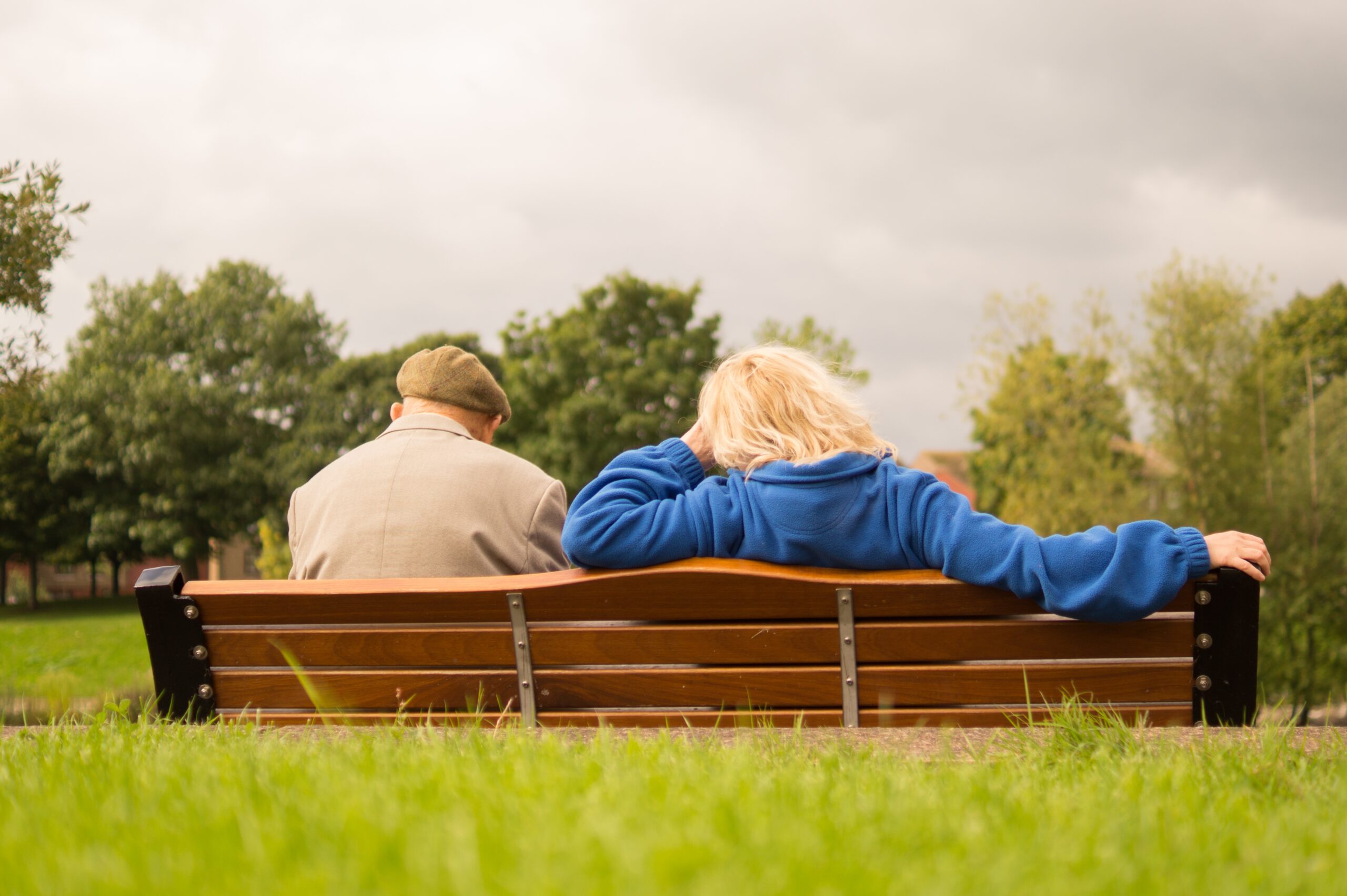 Two people sitting on a bench discussing challenges of aging.